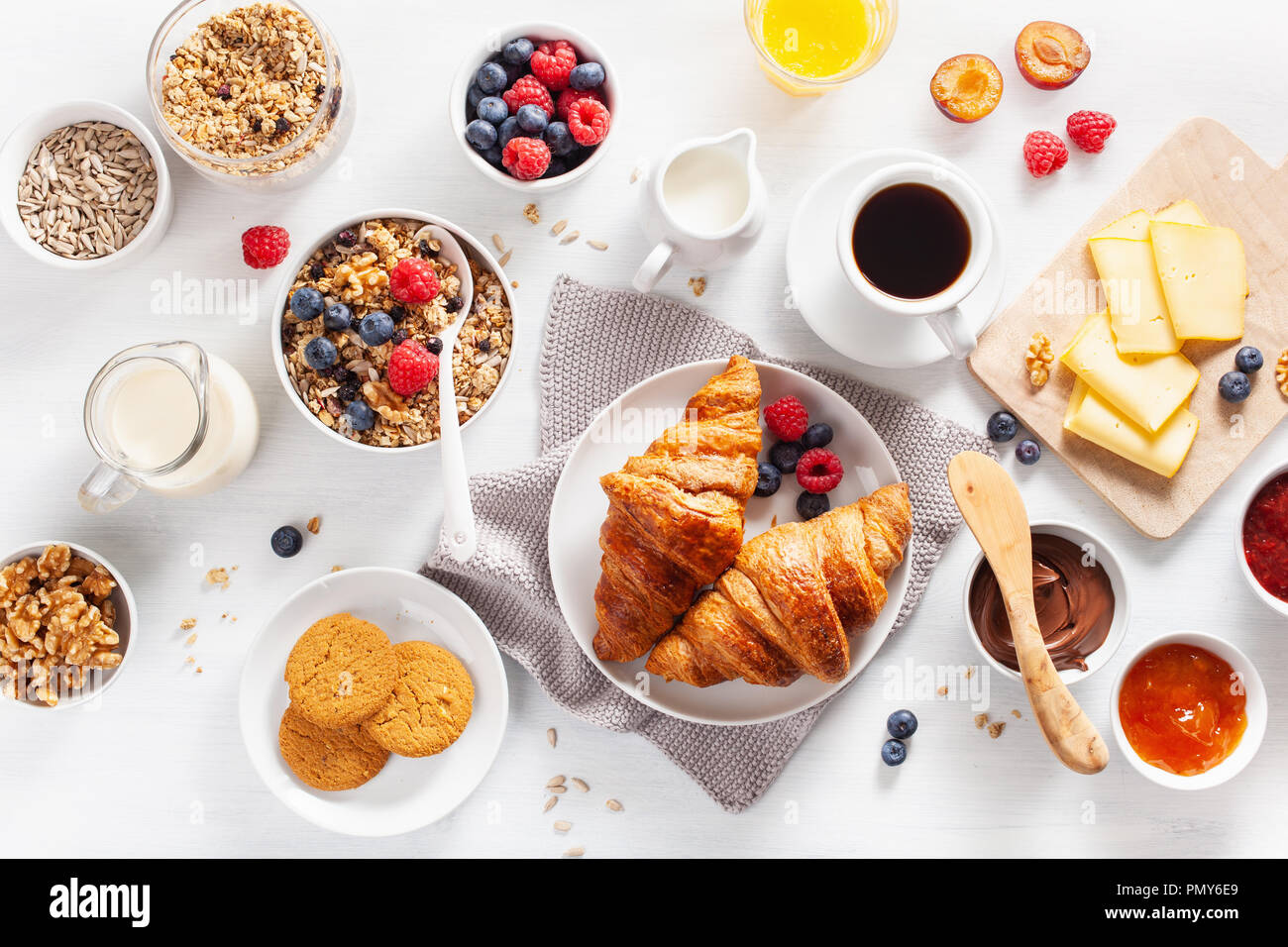 healthy breakfast with granola, berry, nuts, croissant, jam, chocolate