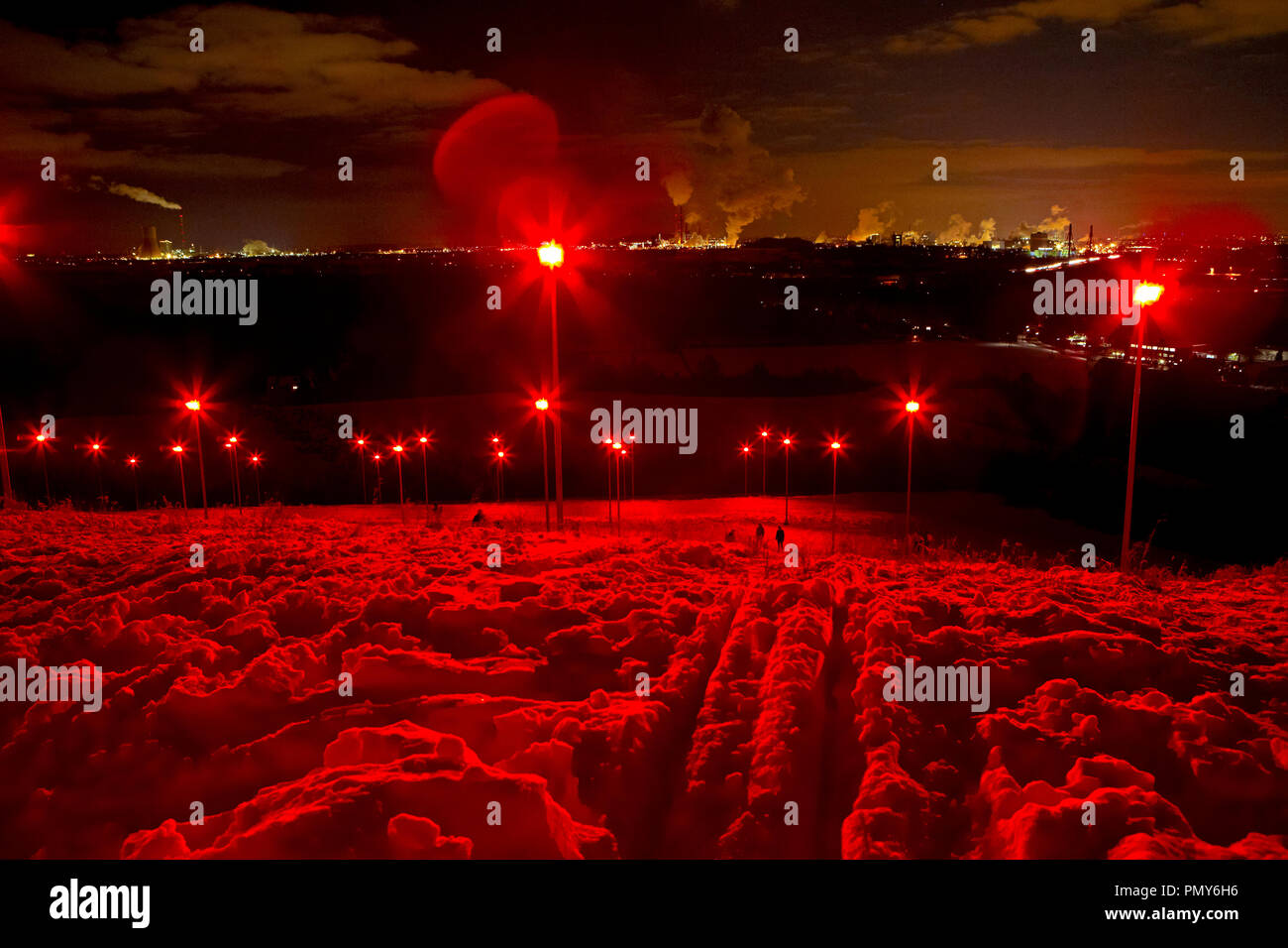 In September 2007, the oversized miner's lamp "Geleucht" was erected as a landmark by the art professor Otto Piene on the Halde Rheinpreußen in Moers. The snow-covered slope of the heap is shrouded in red light by numerous headlamps. Stock Photo