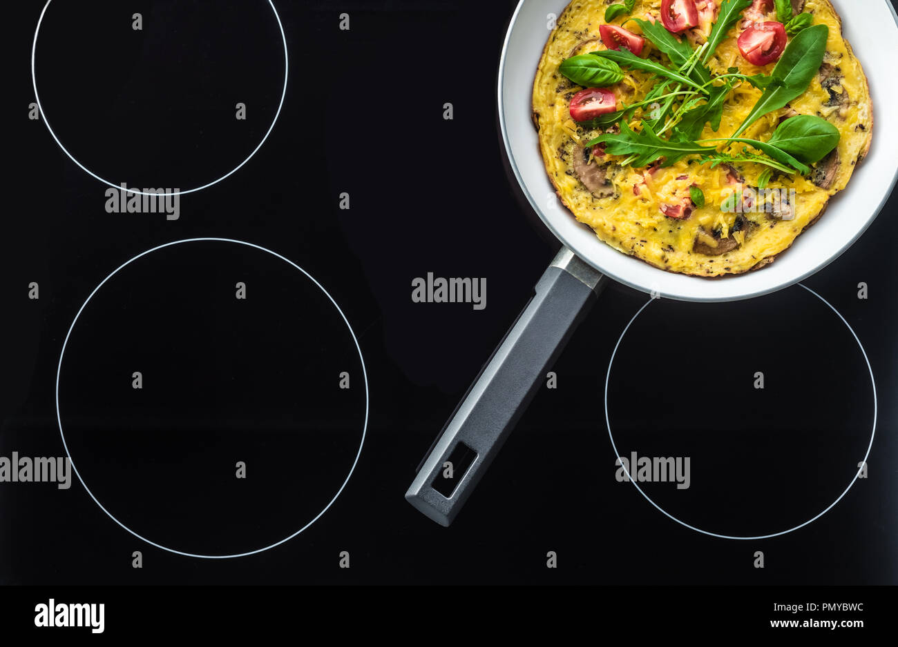 top view of omelette in frying pan cooking on black stove Stock Photo