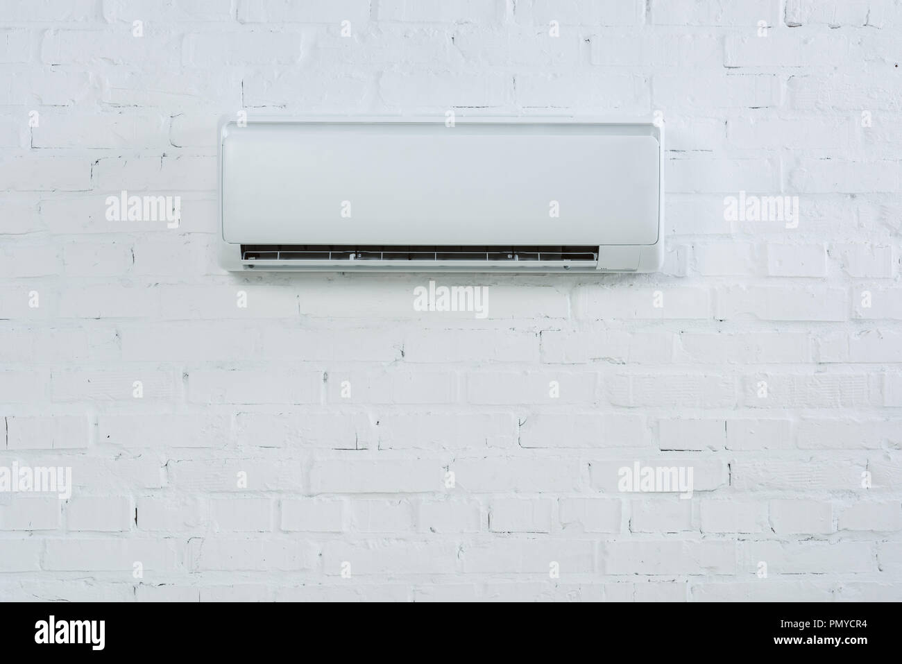 front view of air conditioner hanging on white brick wall Stock Photo ...