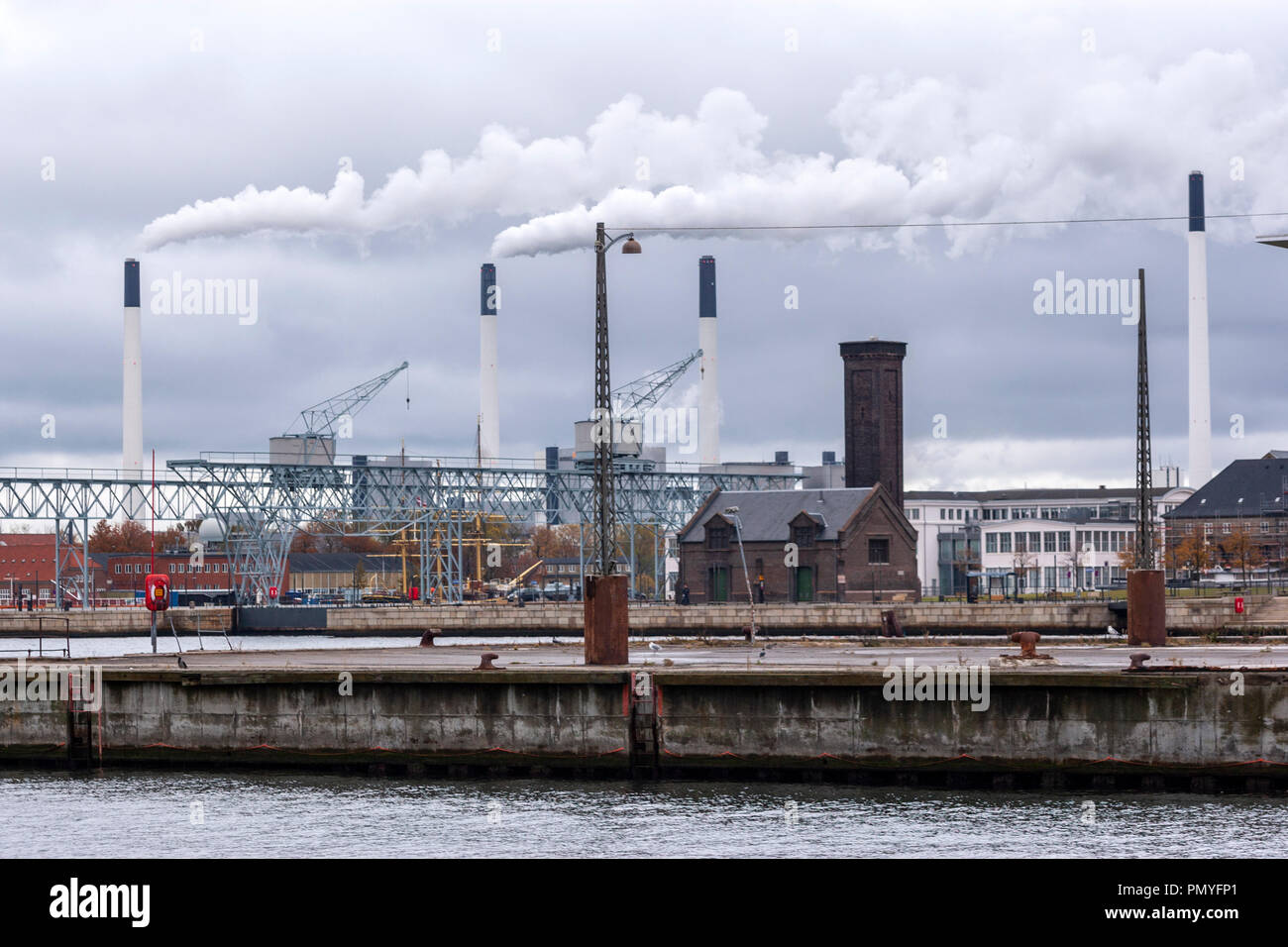 Amager Bakke Waste-to-energy Plant four chimneys with smoke and a old  harbor building, Copenhagen, Denmark Stock Photo - Alamy