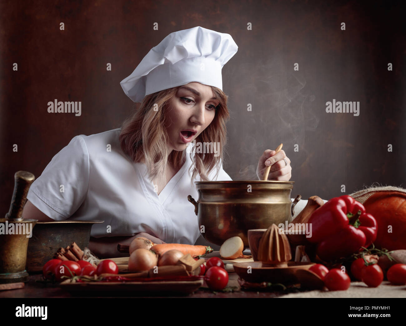 https://c8.alamy.com/comp/PMYMH1/young-beautiful-girl-in-a-chef-uniform-with-old-brass-pan-and-wooden-spoon-tasting-food-on-a-table-various-kitchenware-and-vegetables-PMYMH1.jpg