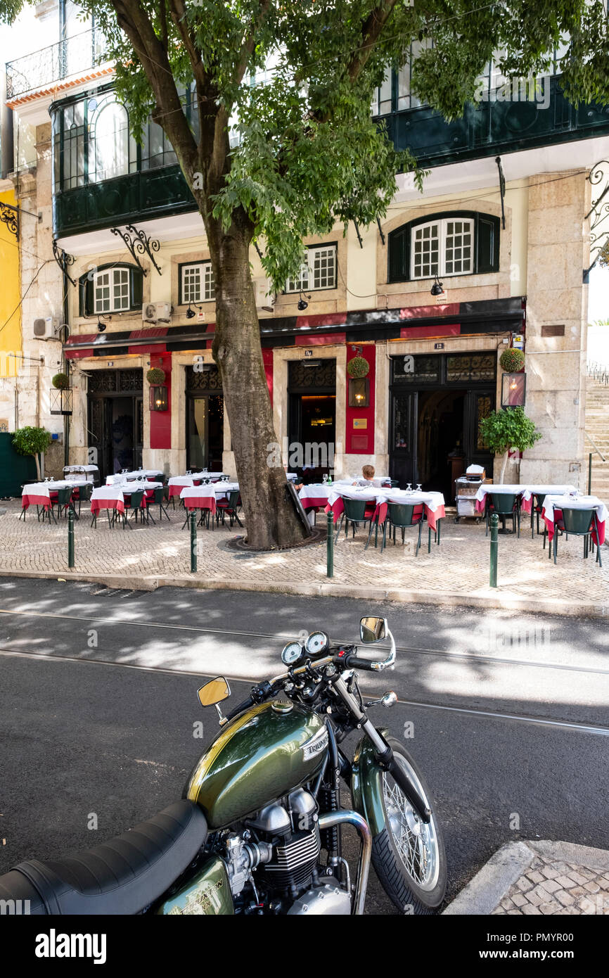 Classic Green Triumph motorbike parked across from a traditional Portuguese Lisbon Restaurant Stock Photo