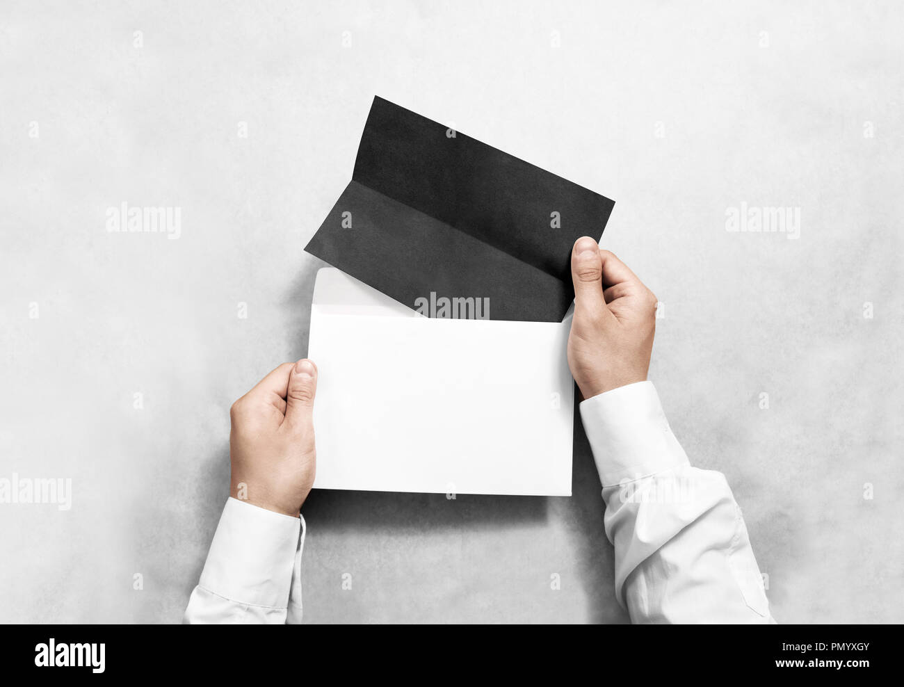 Hand holding black blank envelope and folded leaflet mockup, isolated. Arm hold empty brochure template mock up. Greeting card flyer design. Invitatio Stock Photo