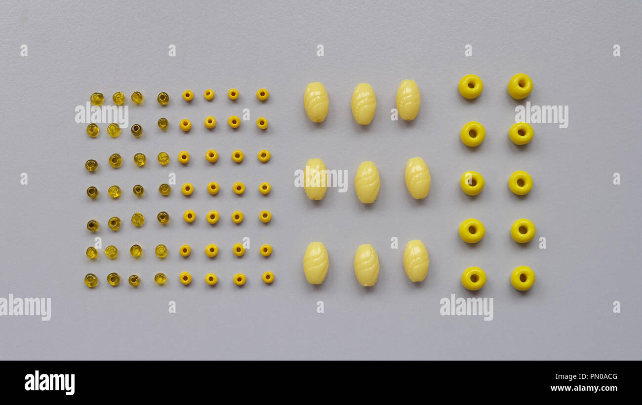 Flat lay of neatly arranged yellow beads of different sizes Stock Photo