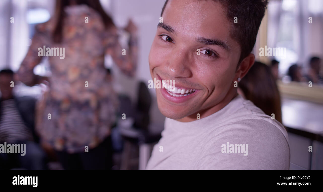Portrait of Handsome young mixed race hipster man smiling at camera with group of friends partying in background Stock Photo