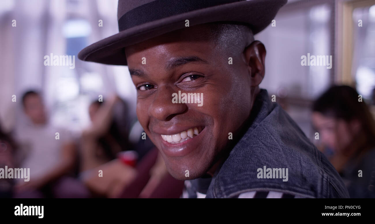 Portrait of Handsome young black hipster man smiling and laughing with group of friends partying in background Stock Photo