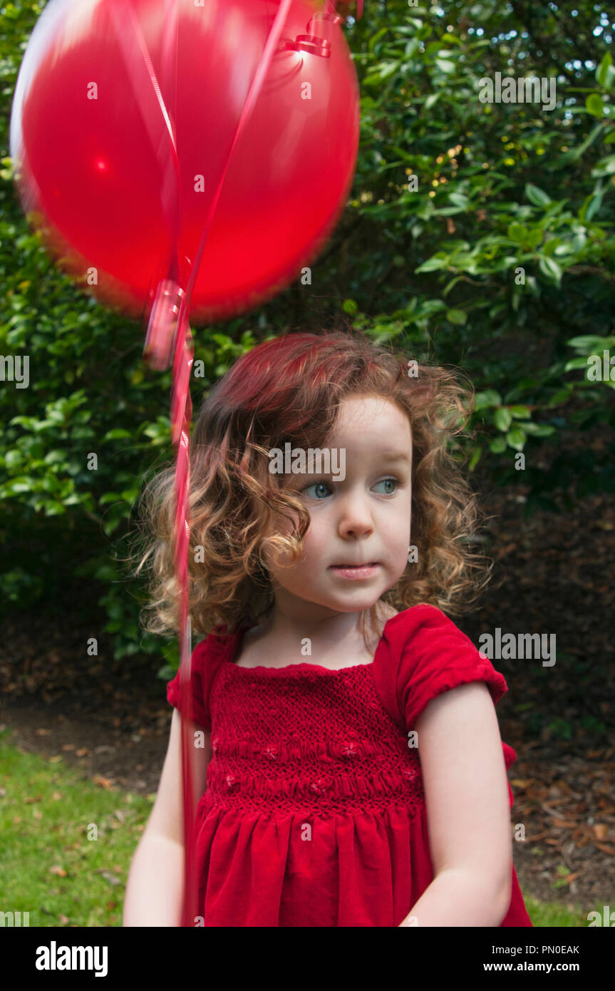 A young girl holding red balloons Stock Photo - Alamy