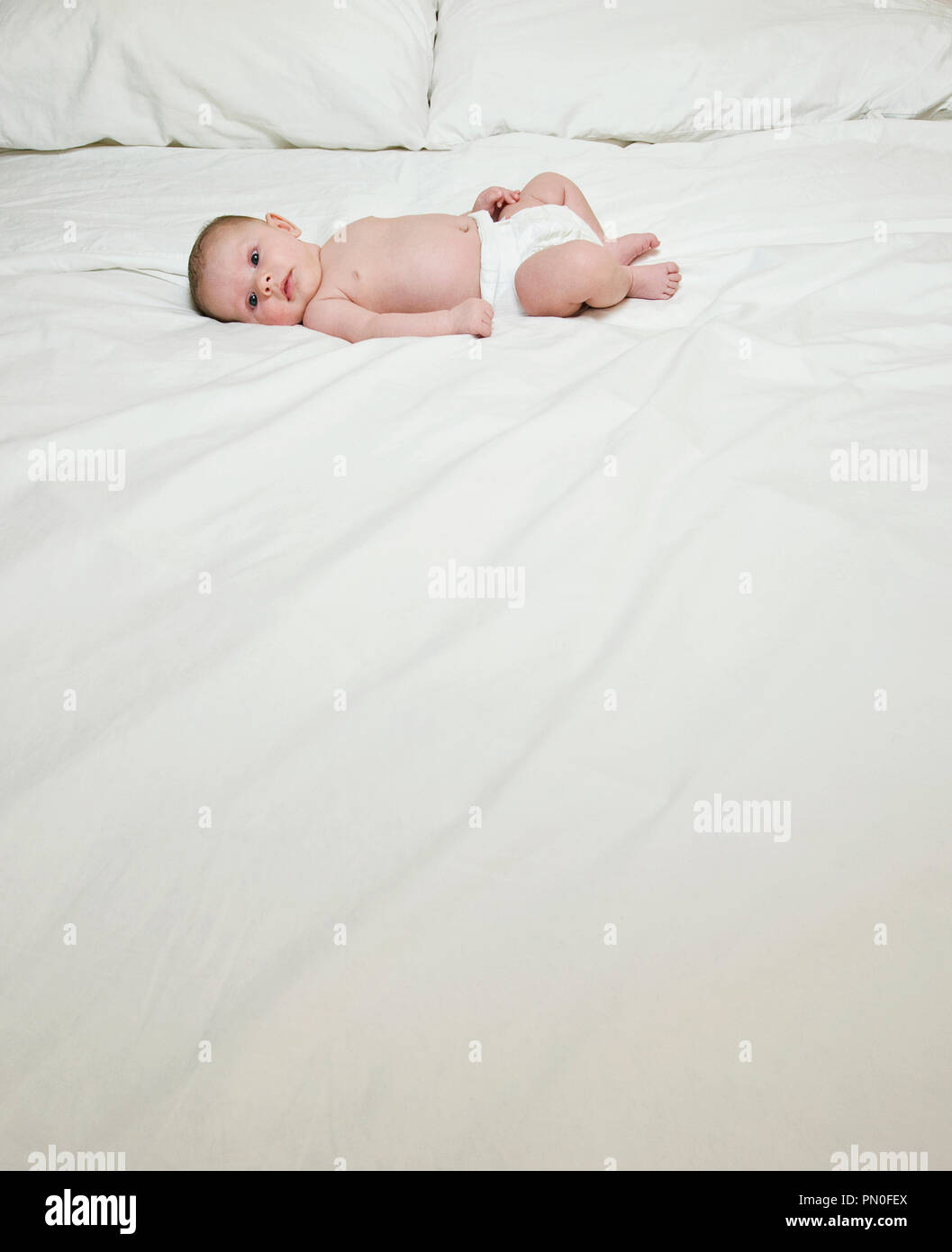 A two month old baby laying on a bed Stock Photo Alamy