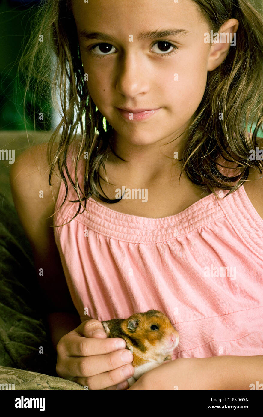 A portrait of a young girl (58 years) holding her pet hamster Stock