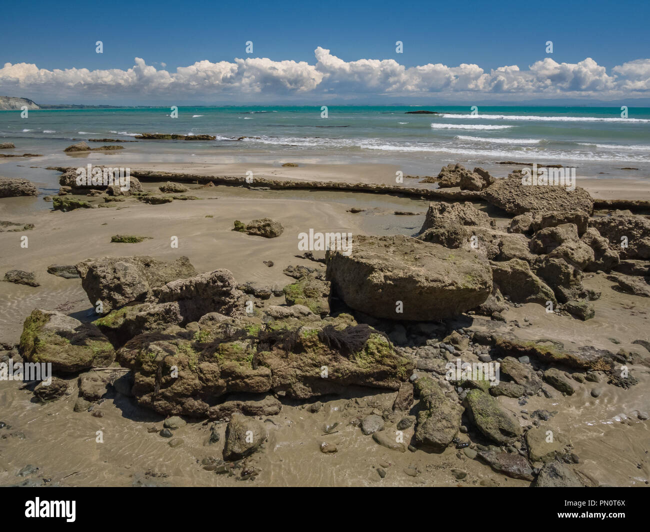 Boulders and sand intermix on Cape Kidnappers Gannet Beach on a beautiful spring day along Hawkes Bay in New Zealand. Stock Photo