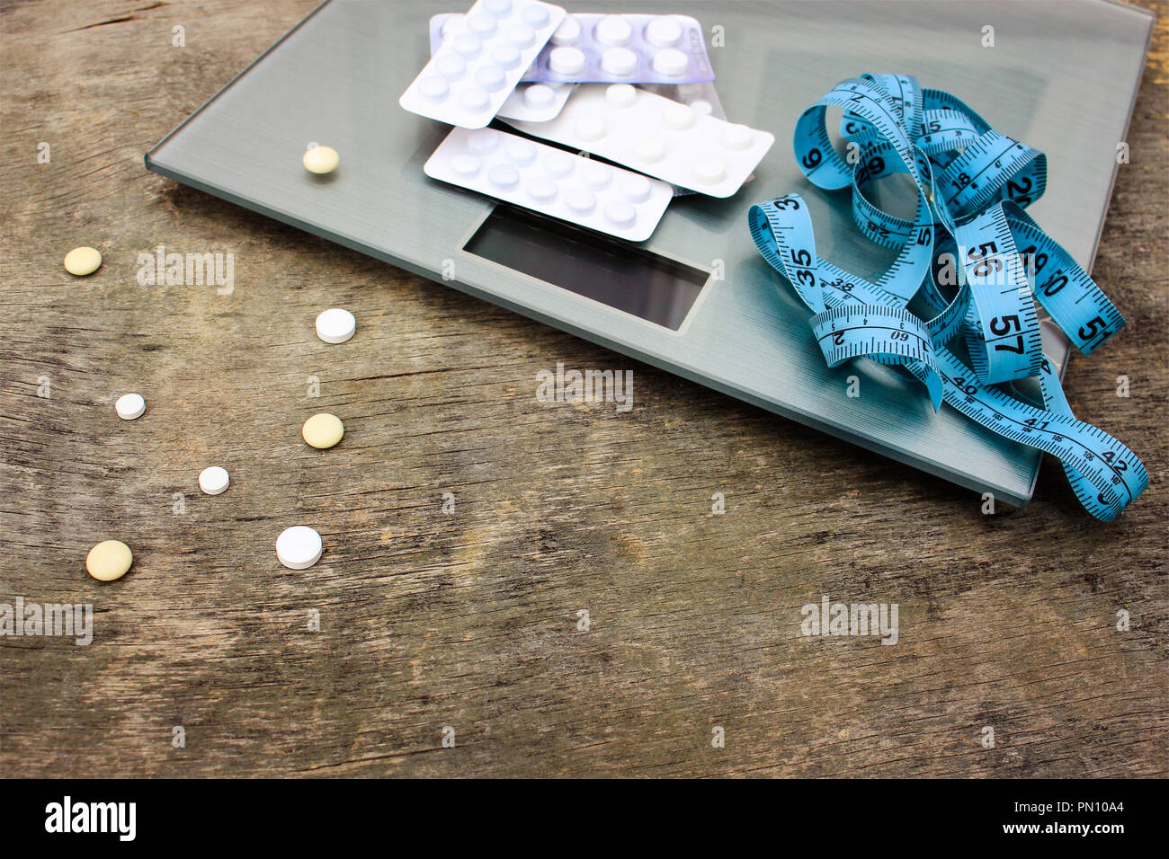 Measuring tape, pills and scales on wooden background. The concept of diet pills. Stock Photo