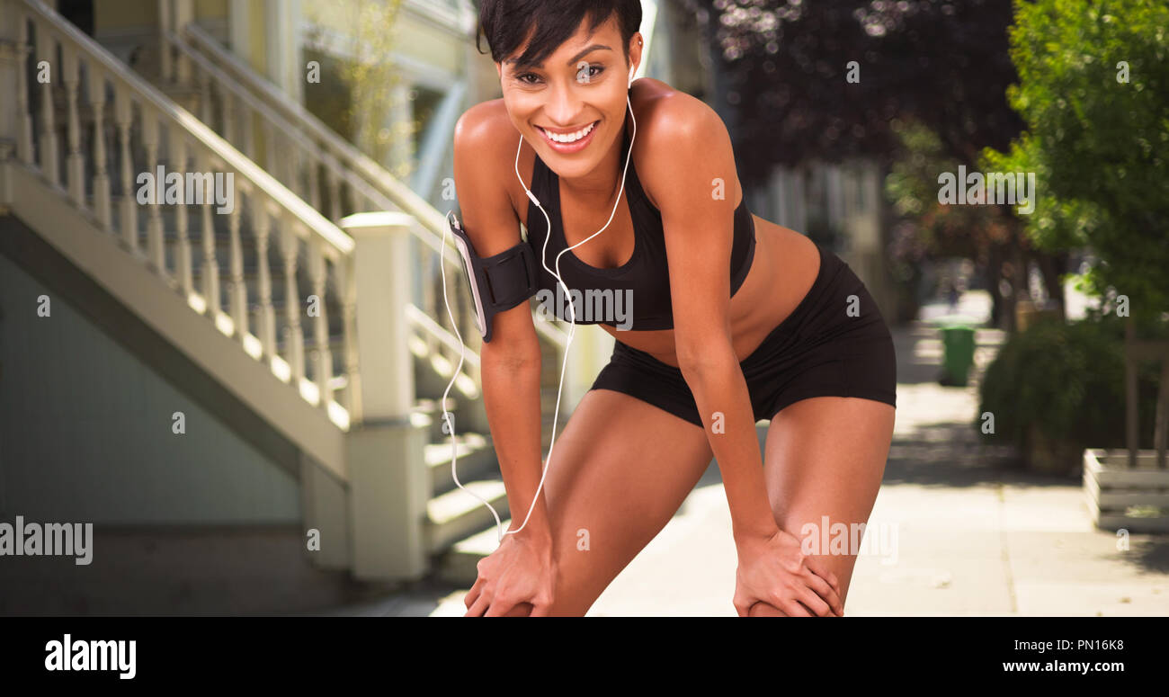Athletic healthy black woman runner resting during jog on city street Stock Photo