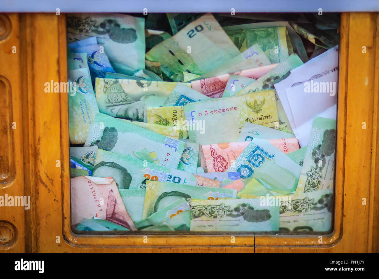 Thai banknotes money in the wooden donation box at the Buddhist 