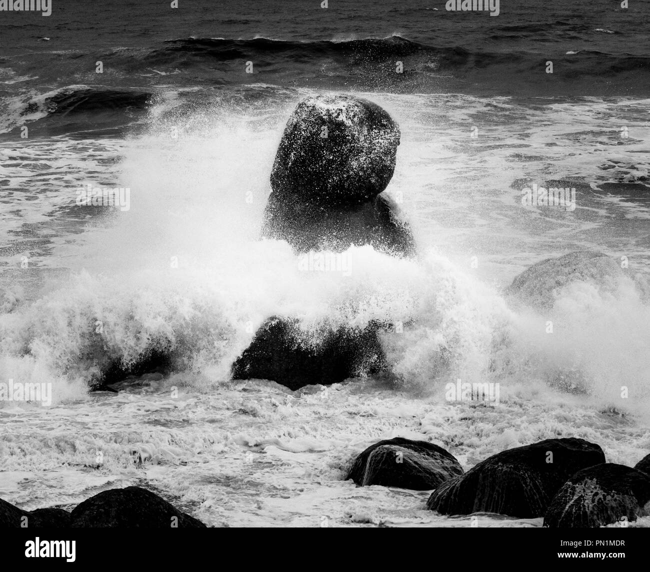 Ocean waves crash in a odd-shaped rock. Stock Photo