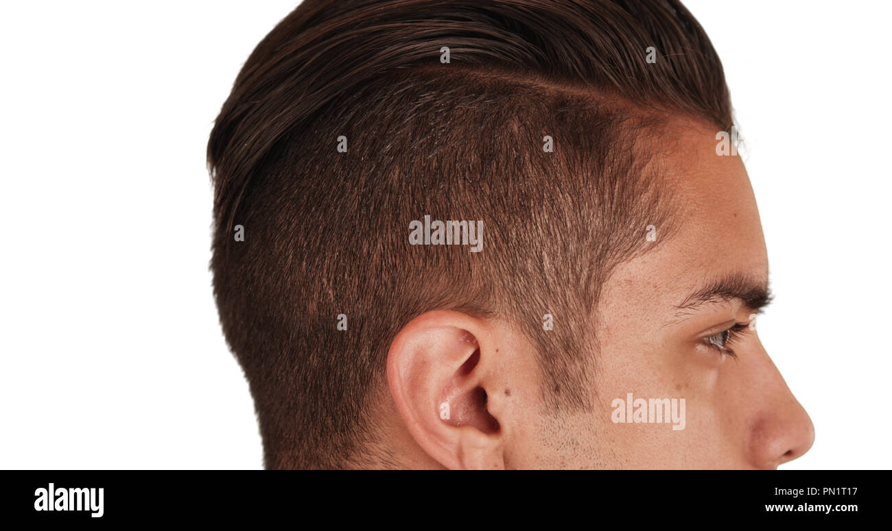 Close up Side view of Hispanic man with cool undercut standing with white background Stock Photo