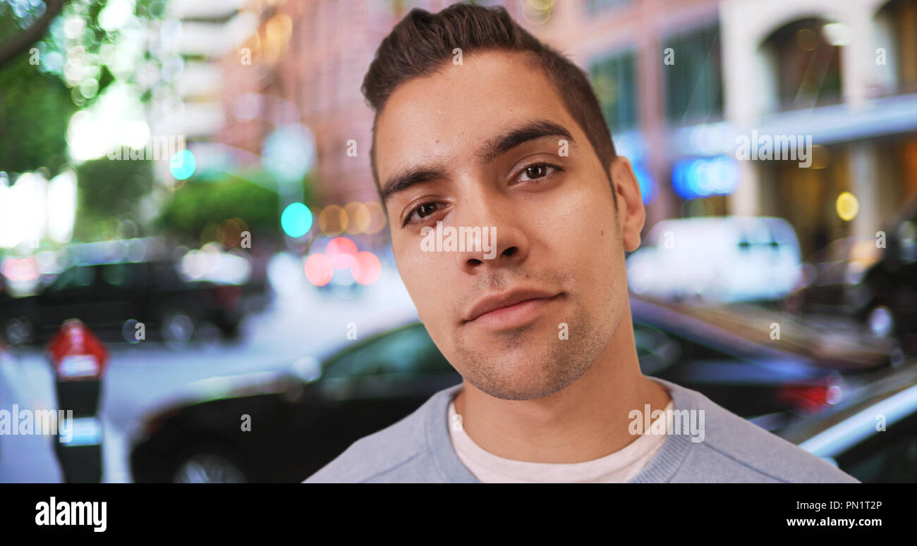 Wide angle close up shot of Hispanic man standing outside on street looking at camera Stock Photo