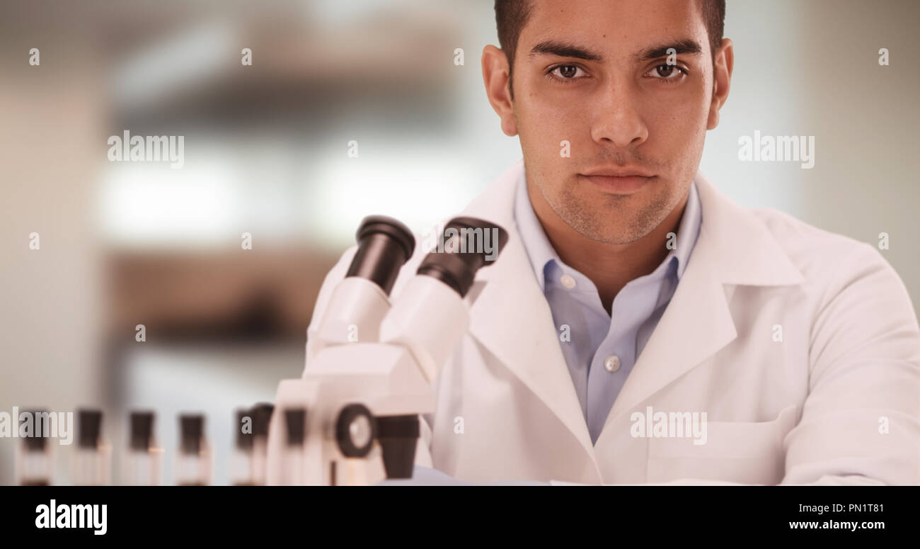 Portrait of Millennial Hispanic medical research scientist in lab using microscope Stock Photo