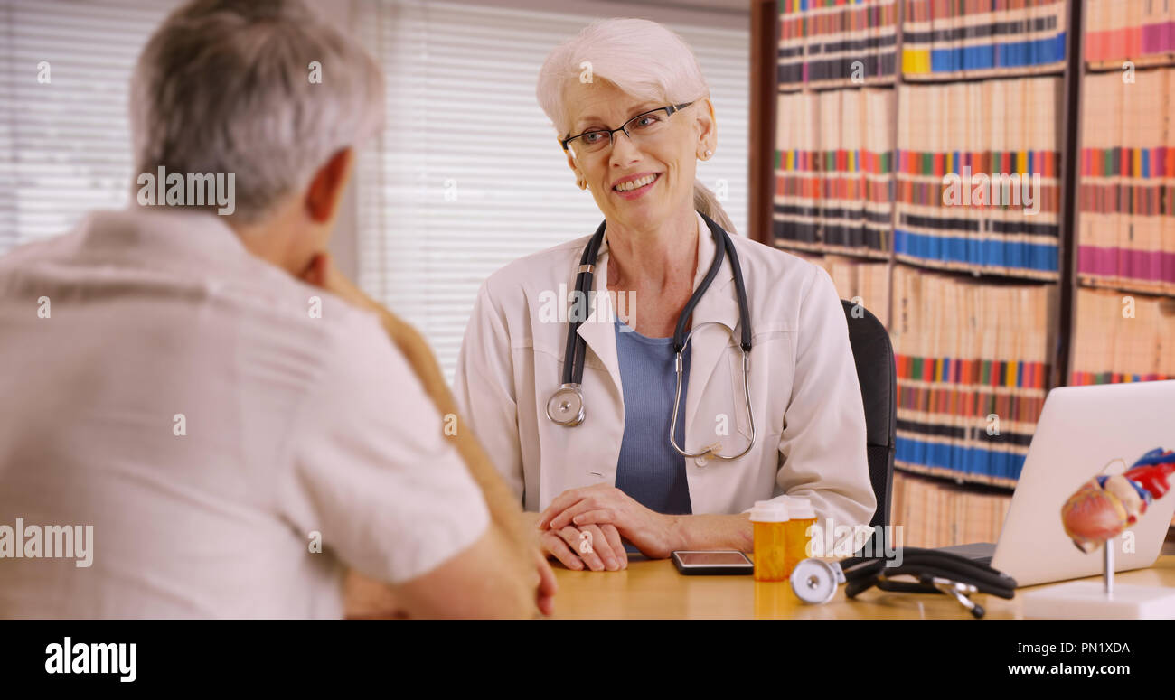 Educated woman doctor talking with patient in her office Stock Photo