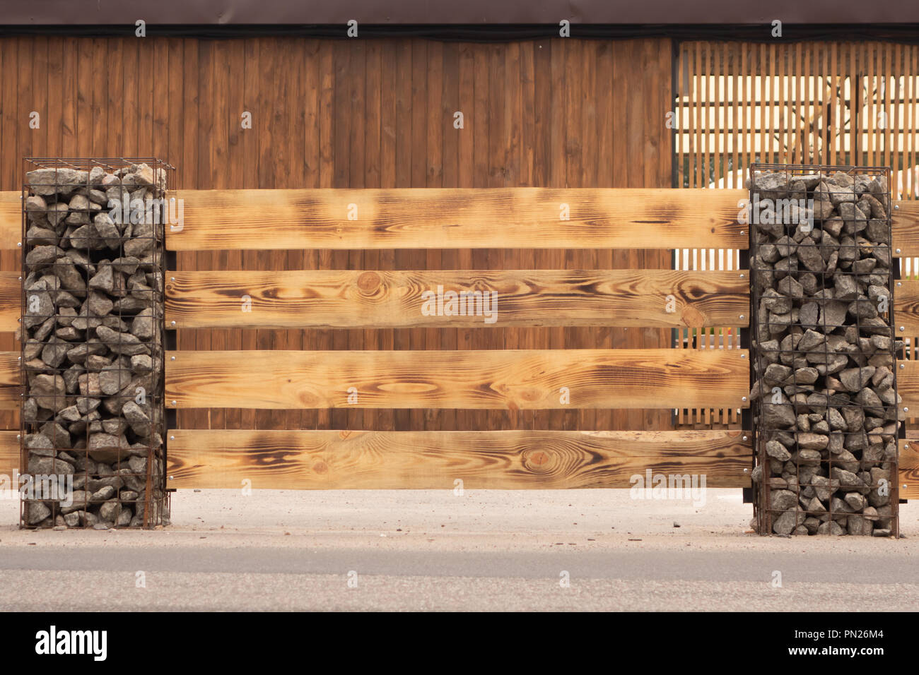 Wooden fence made of horizontal boards with stone pillars. The pillars are  made of a metal frame with granite gravel embedded in it. Option of decorat  Stock Photo - Alamy, image size:1300x956