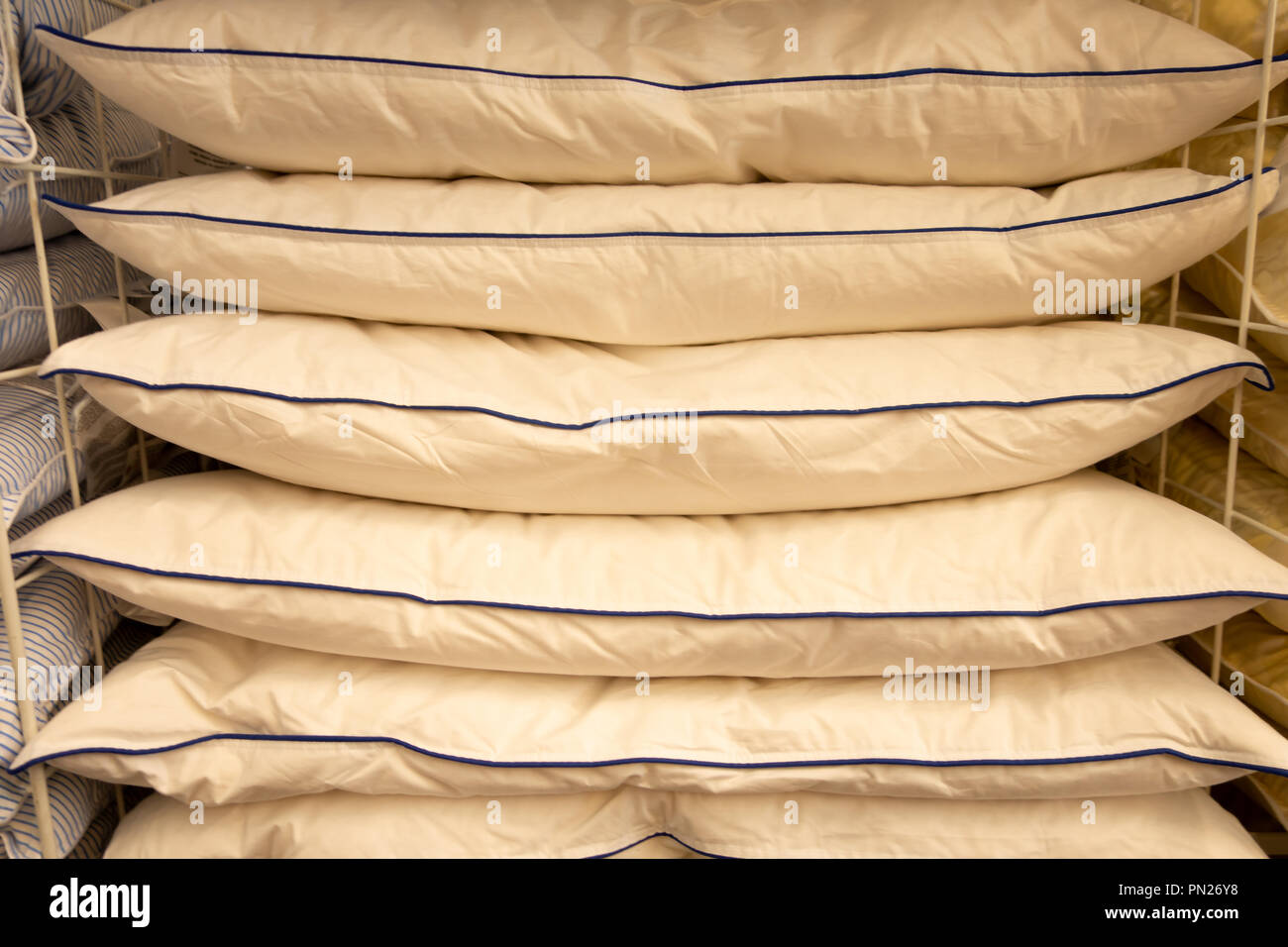 Stack of warm plaid and pillows on white shelf against striped wall background. Stock Photo