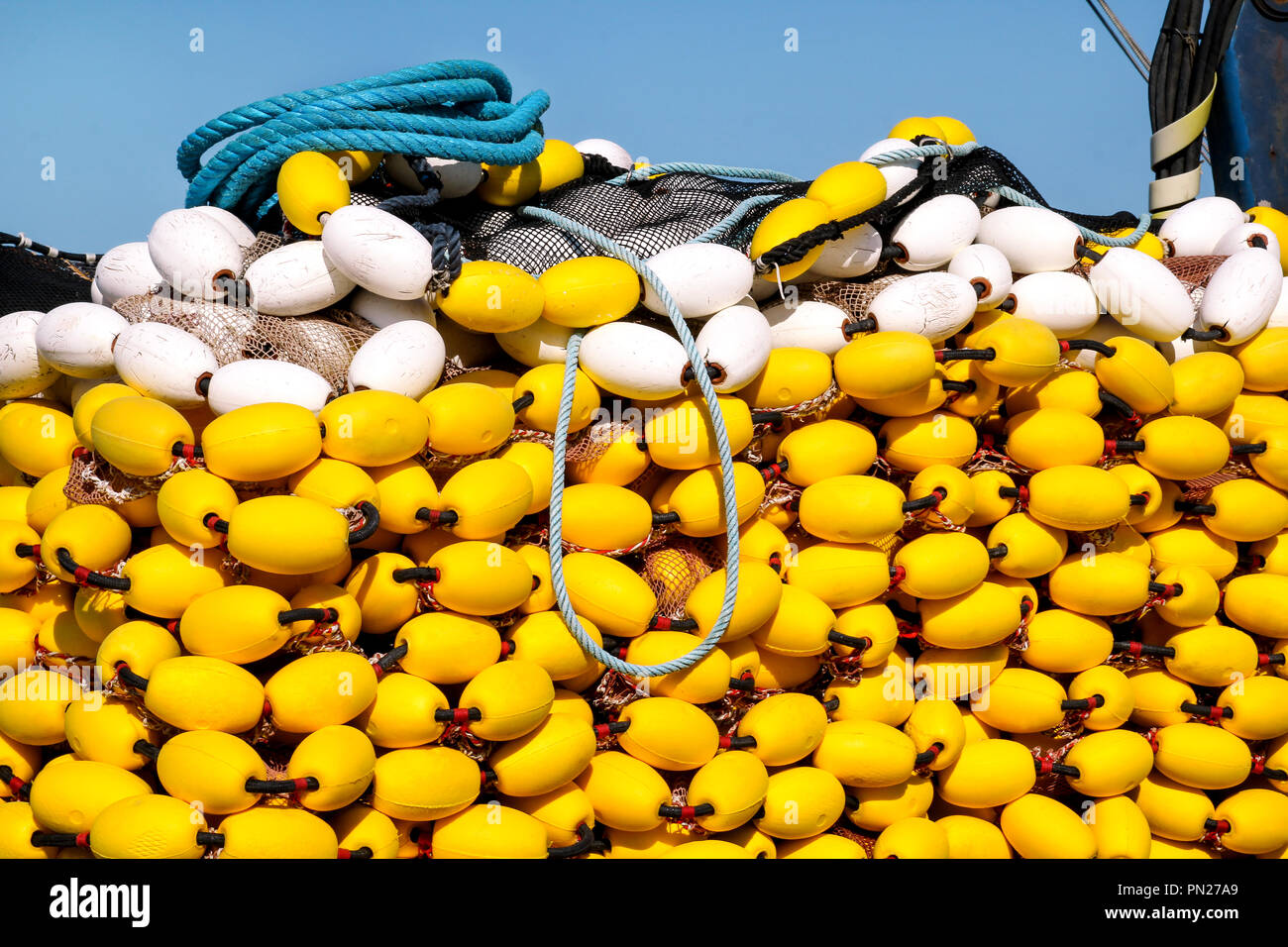 Yellow floats on the pile, covering fishing nets on the blue boat in ...