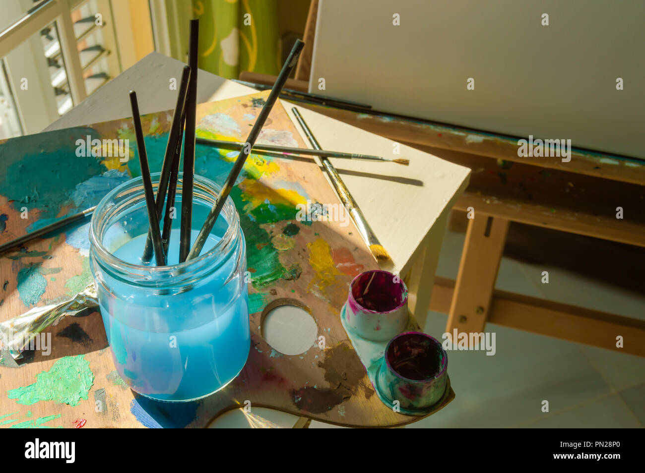 Materials to paint with sunbeams of a window jar with water to clean
