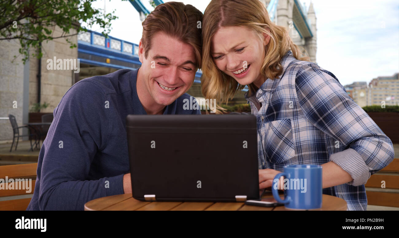 Caucasian man and woman in London using laptop outdoors smiling Stock Photo