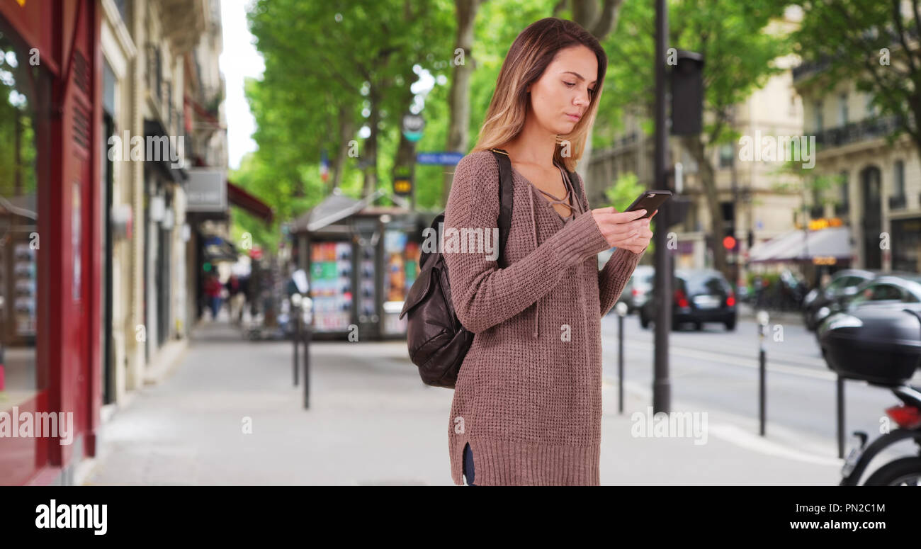 Pretty Caucasian woman walks down the street using smartphone for ...