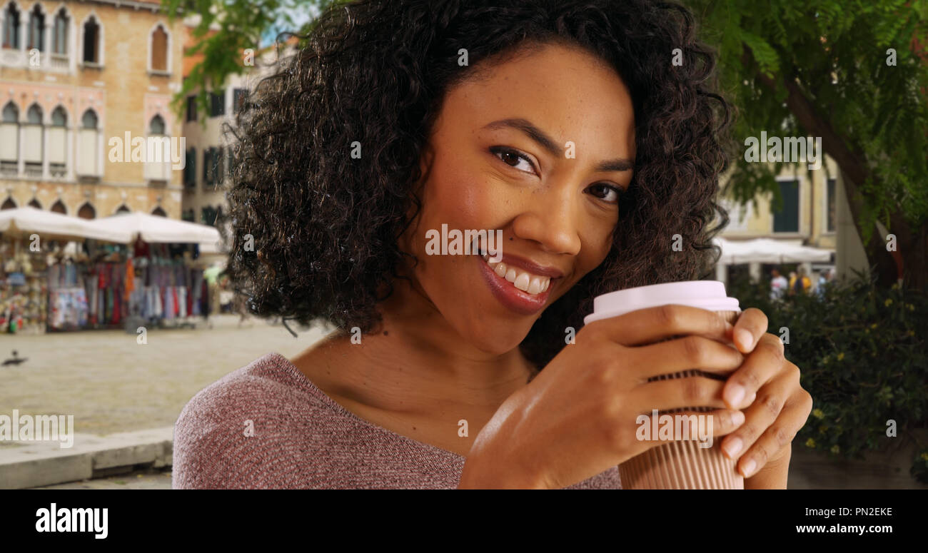 Happy young black woman tourist drinking coffee in Venice out of paper ...