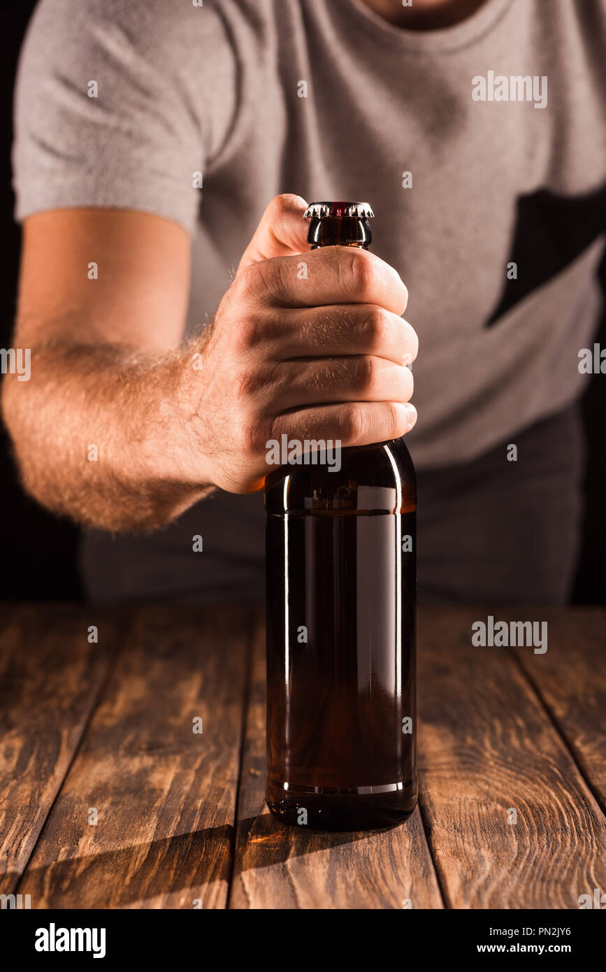 cropped image of man opening beer bottle at wooden table Stock Photo