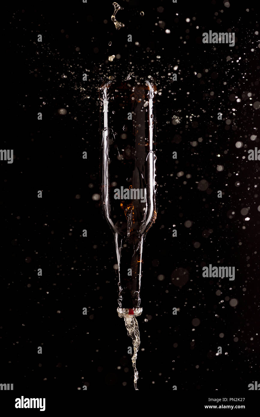 beer with splashes and bottle upside down falling isolated on black
