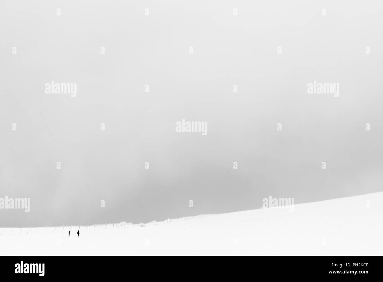 A very minimalistic view of two distant people over a mountain covered by snow Stock Photo