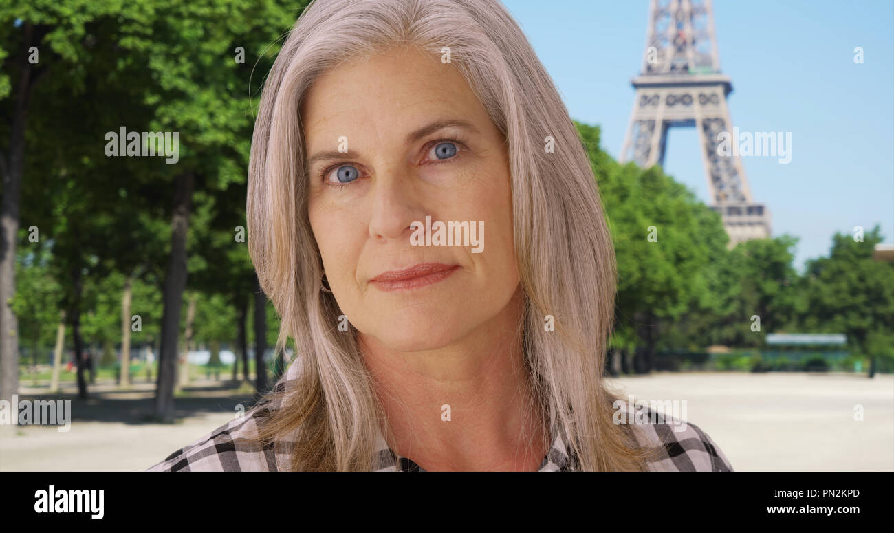 Old Caucasian female looks up longingly near the Eiffel Tower Stock Photo