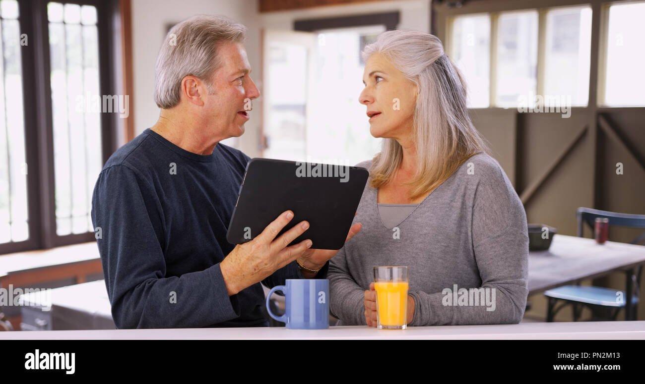 Elderly caucasian couple looking at tablet computer during breakfast Stock Photo