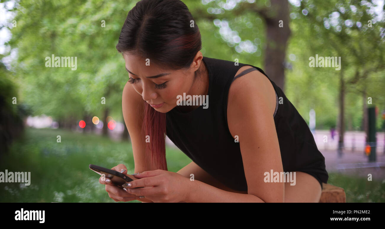 Japanese woman texting on mobile phone at the park Stock Photo Alamy