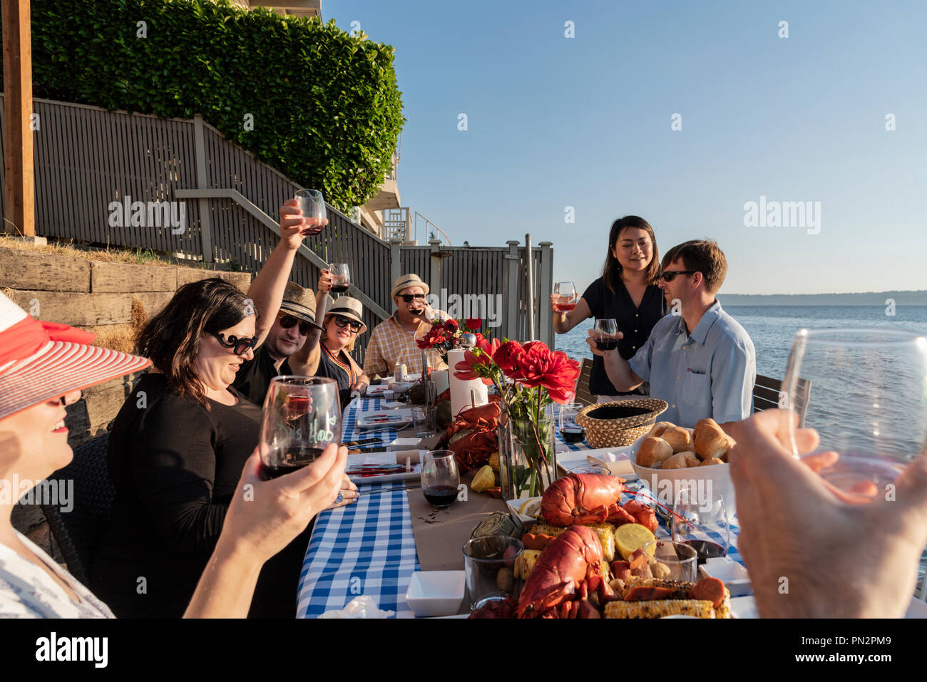 Friends dining al fresco by the sea eating a lobster seafood dinner Stock Photo