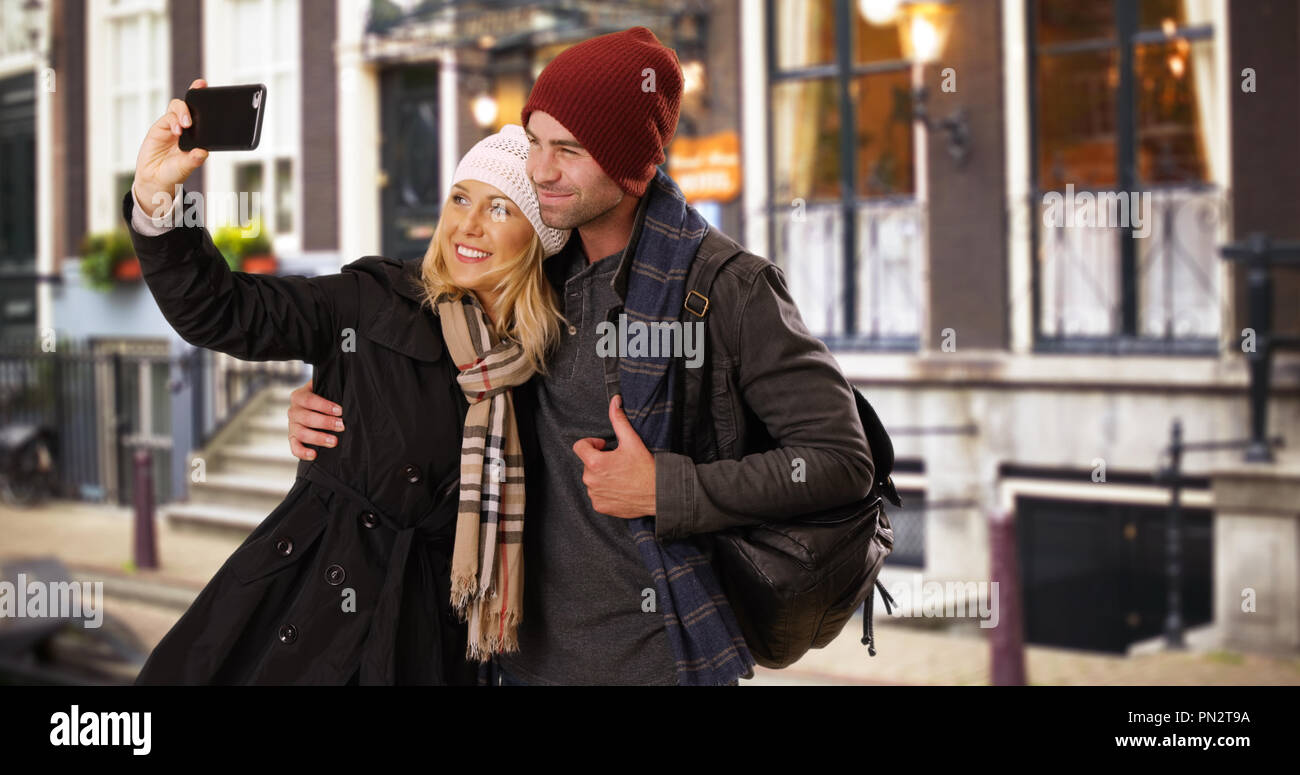 Happy yuccie couple taking a selfie outdoors in the city Stock Photo