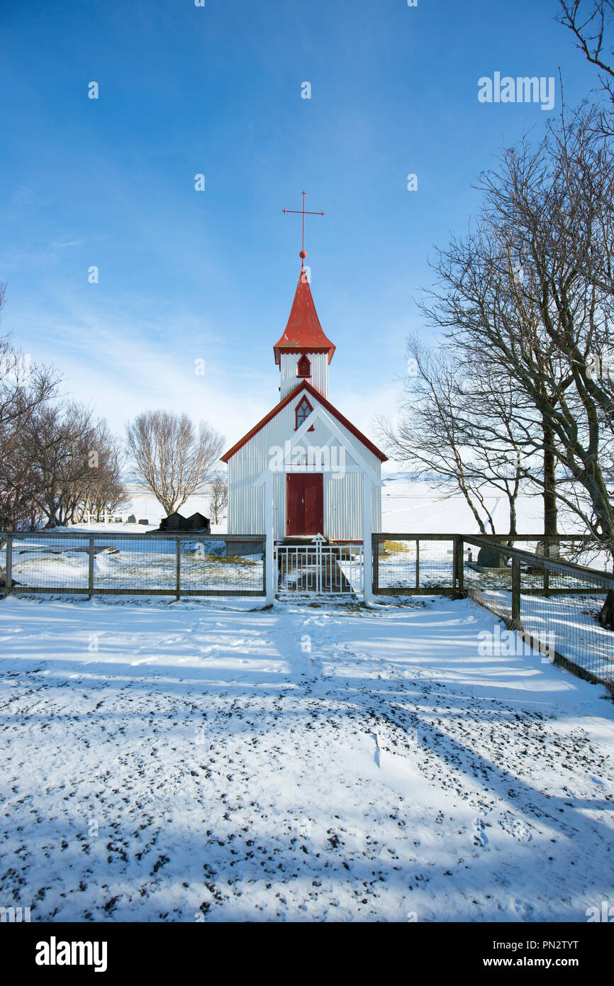 Quaint typical traditional church Braedratungukirkja with red roof in snowy landscape in Iceland Stock Photo