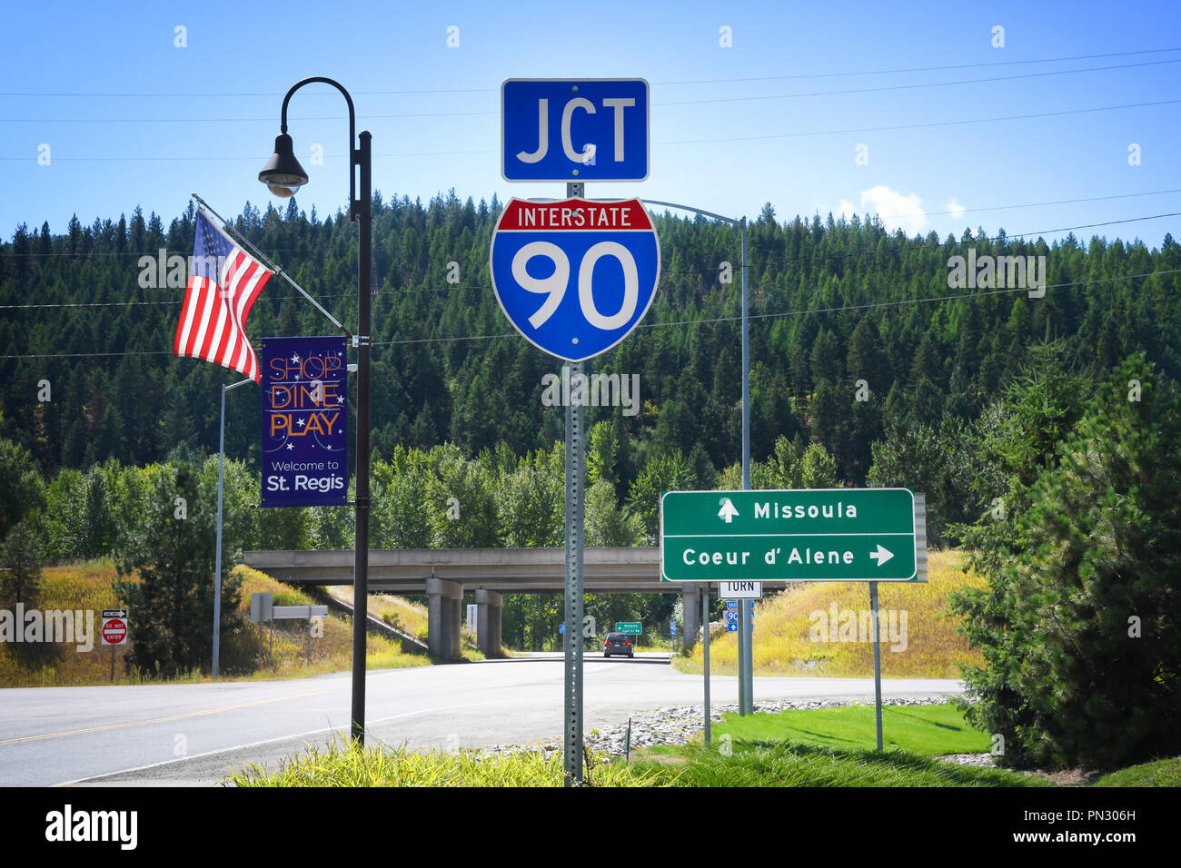 ST. REGIS, MONTANA, USA: September 1, 2018: An American flag and road and welcome signs at the juntion of Interstate 90 and Montana Highway 135 Stock Photo