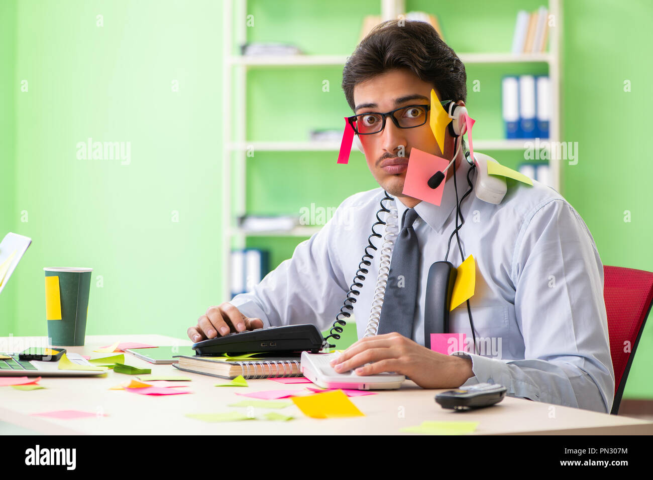 Young help desk operator working in office with many conflicting