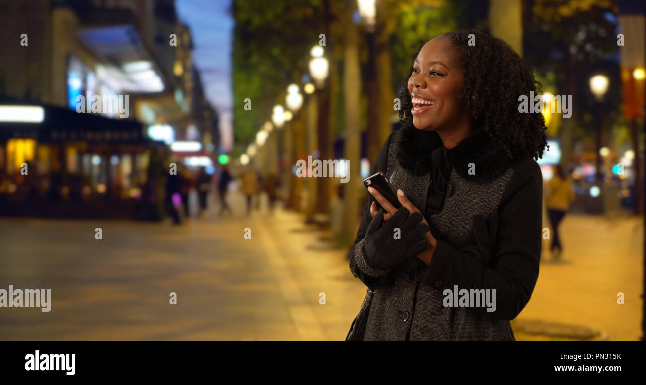 Pretty black woman smiling on city street at night Stock Photo - Alamy