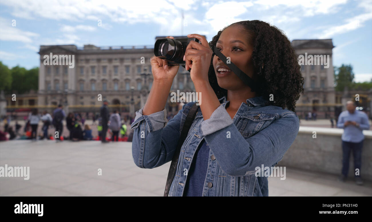 Portrait of excited tourist taking photos with camera outside Buckingham Palace Stock Photo