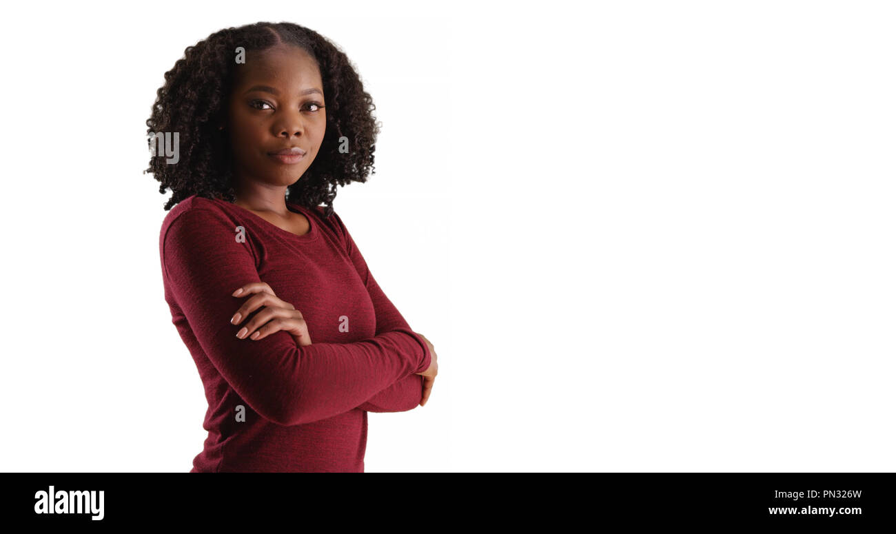 Confident young black woman poses with arms crossed in studio with ...