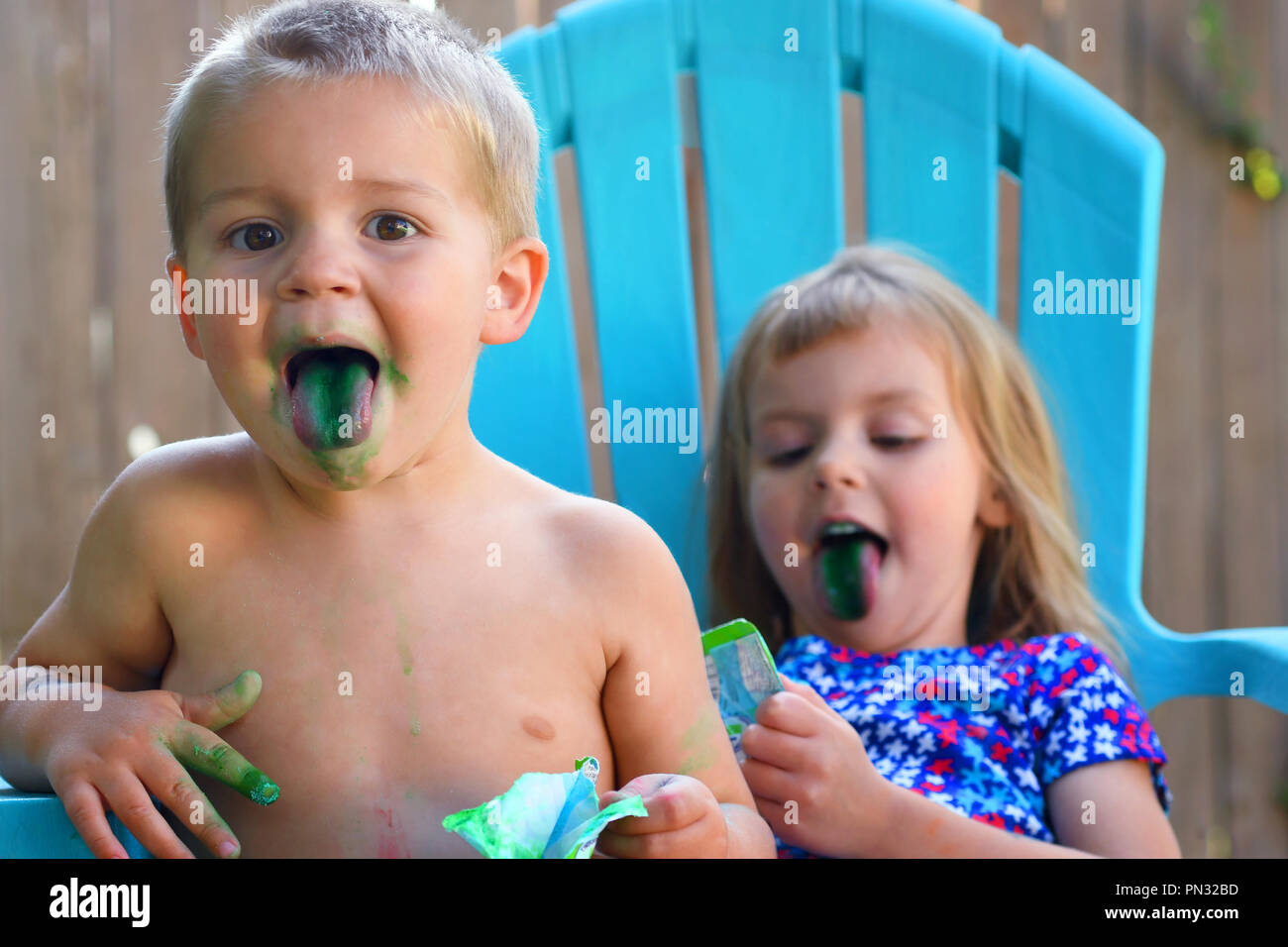 Two toddlers eating candy with blue tongues Stock Photo
