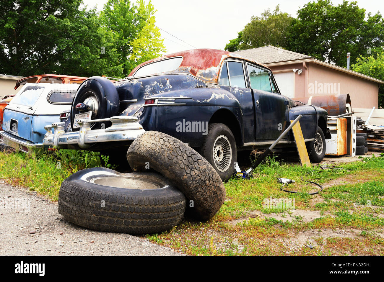 Old cars in various states of repair behind a residential garage Stock Photo