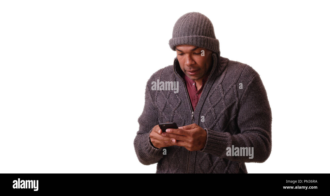 African American man stands trembling on a white background on his smart phone Stock Photo