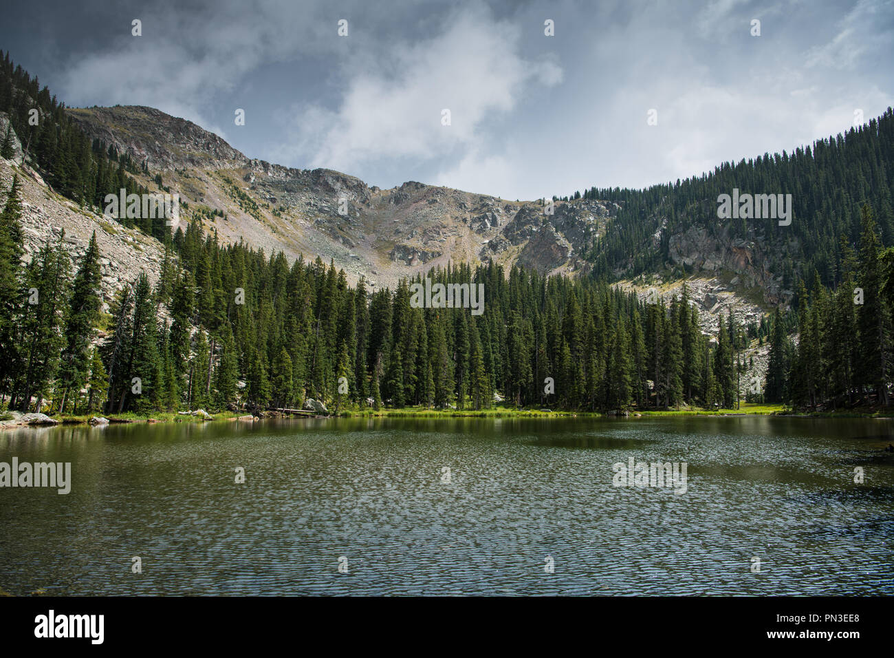 Dark and dramatic sky and clouds over alpine lake and mountain peaks Nambe Lake in the Santa