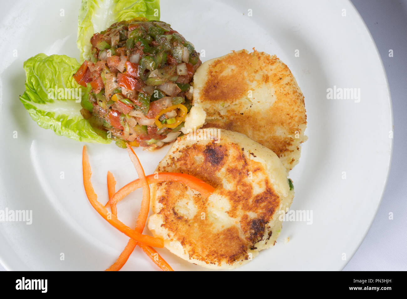 Plated entree dish of sauteed cheese potato cake with a chili and pepper salsa Stock Photo