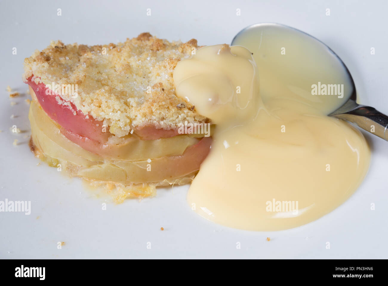 Classic English dessert of Apple crumble with Custard sauce Stock Photo